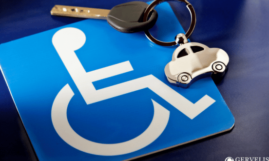 A blue disabled parking placard lying beside a car key on a keyring.
